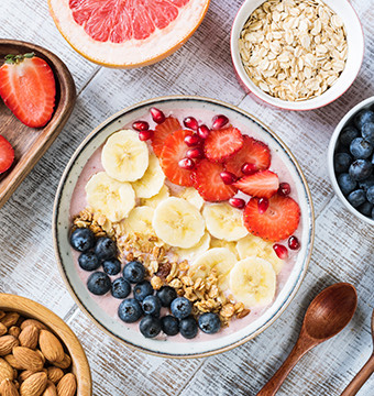 Top view of a dish with strawberries, bananas, blueberries, oats flakes and yogurt
