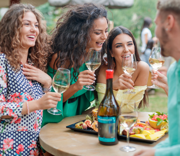 view of a group of friends laughing, eating and drinking together
