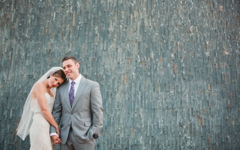 newlyweds standing in front of a gray wall