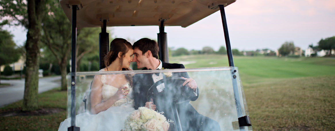 couple in a golf cart with wedding gowns and kissing