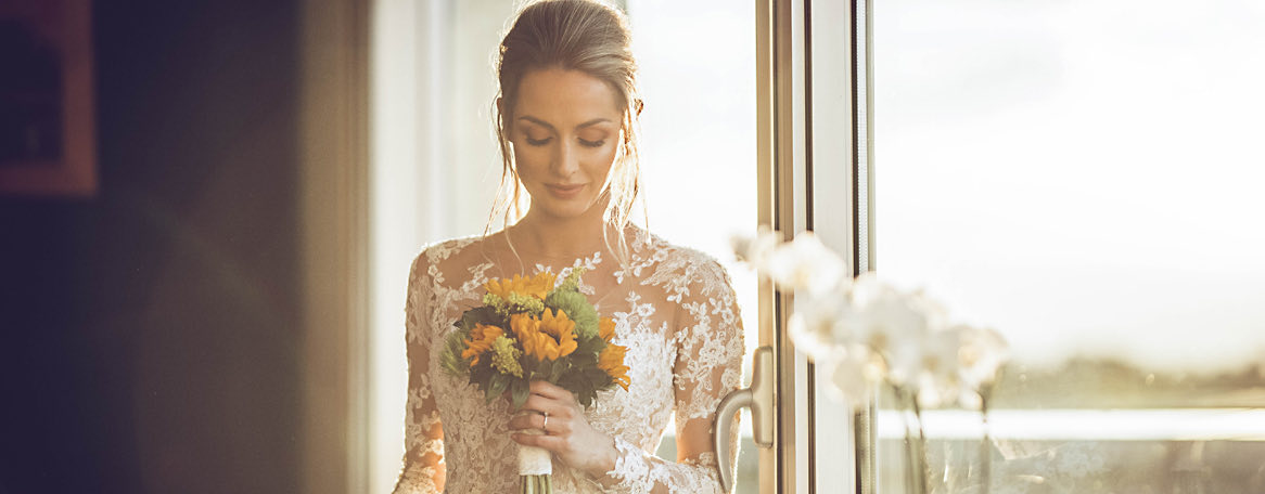 bride posing by a window with a bouquet of flowers