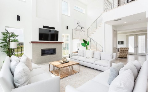 bright living room area with white couches and a chimney