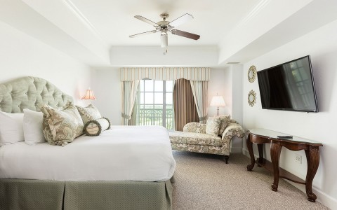 hotel room with king bed and flat screen tv and a couch leaned against the window