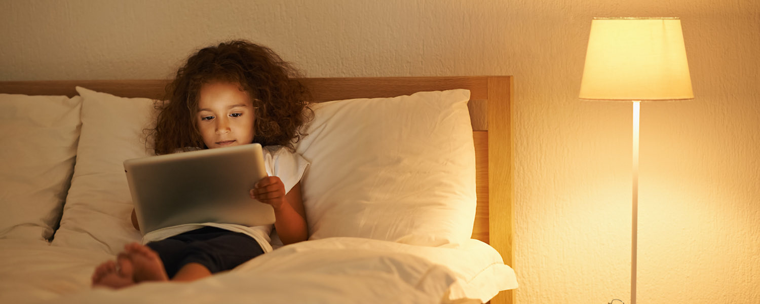little girl reading a book in bed