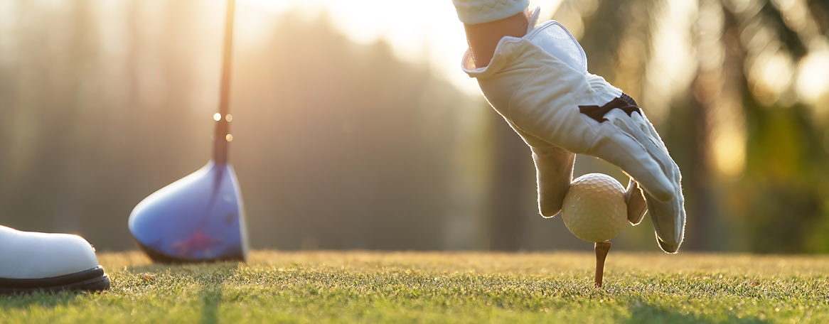 gloved hand placing golf ball on a put