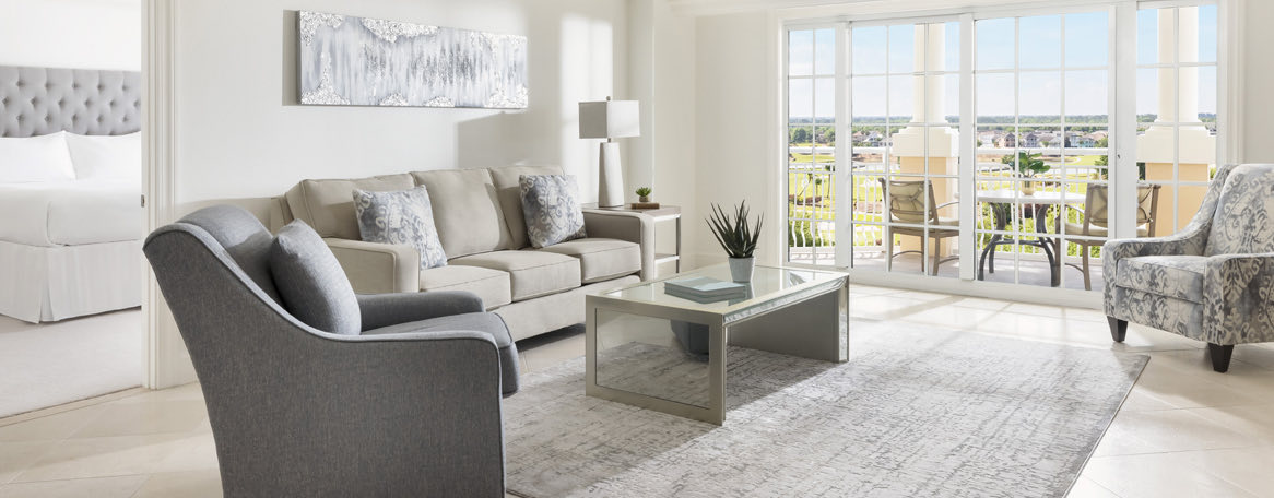 an elegant living room with gray chairs and sofa that overlooks the golf course