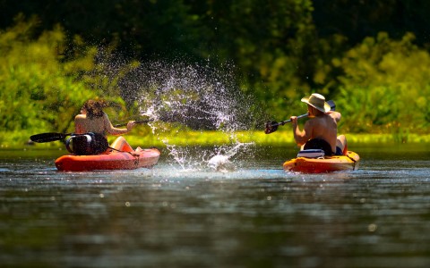 two people in kayaks splashing eachother