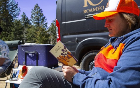 A man reading a book next to the roameo van