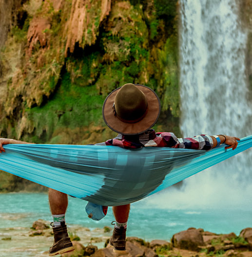 person on a hammock by a waterfall