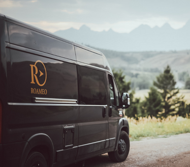 View of a black roameo van with the mountains in the background