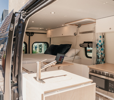 View of the indoors of a Roameo van with a kitchen and a bad
