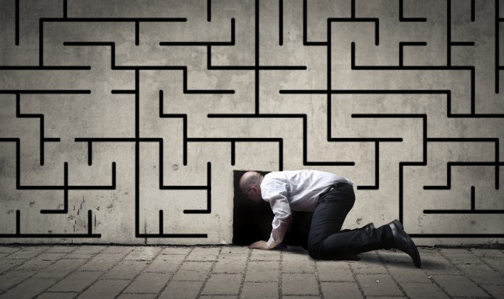 man crawling into a hole on a maze wall