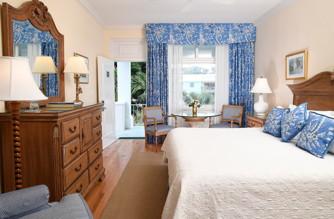 Room with king bed, wooden dresser & light blue accents on pillows & curtains