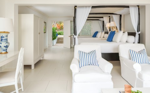 double bed room with white beds and chairs and blue accents