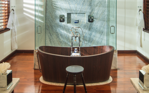 brown wooden bathtub in front of a blue marble shower