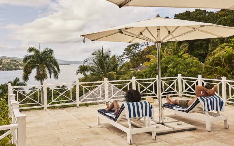 couple lounging on chairs with umbrella looking at the view 