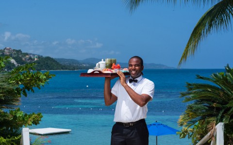 View of a happy staff member holding a tray with breakfast 