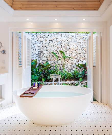 A fancy bathtub on a big illuminated room 