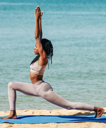 A woman doing a yoga pose next to the seashore