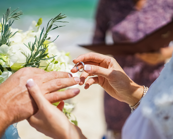 Closeup of a bride putting the ring on the groom's finger