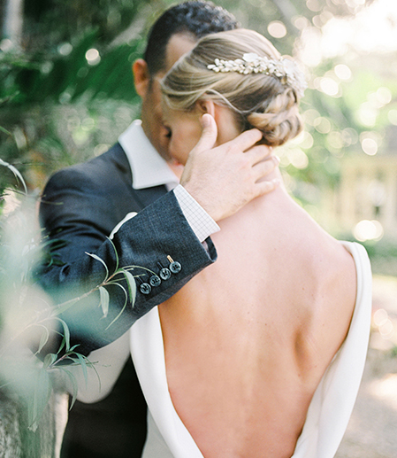 Back view of a bride and a groom hugging outdoors 