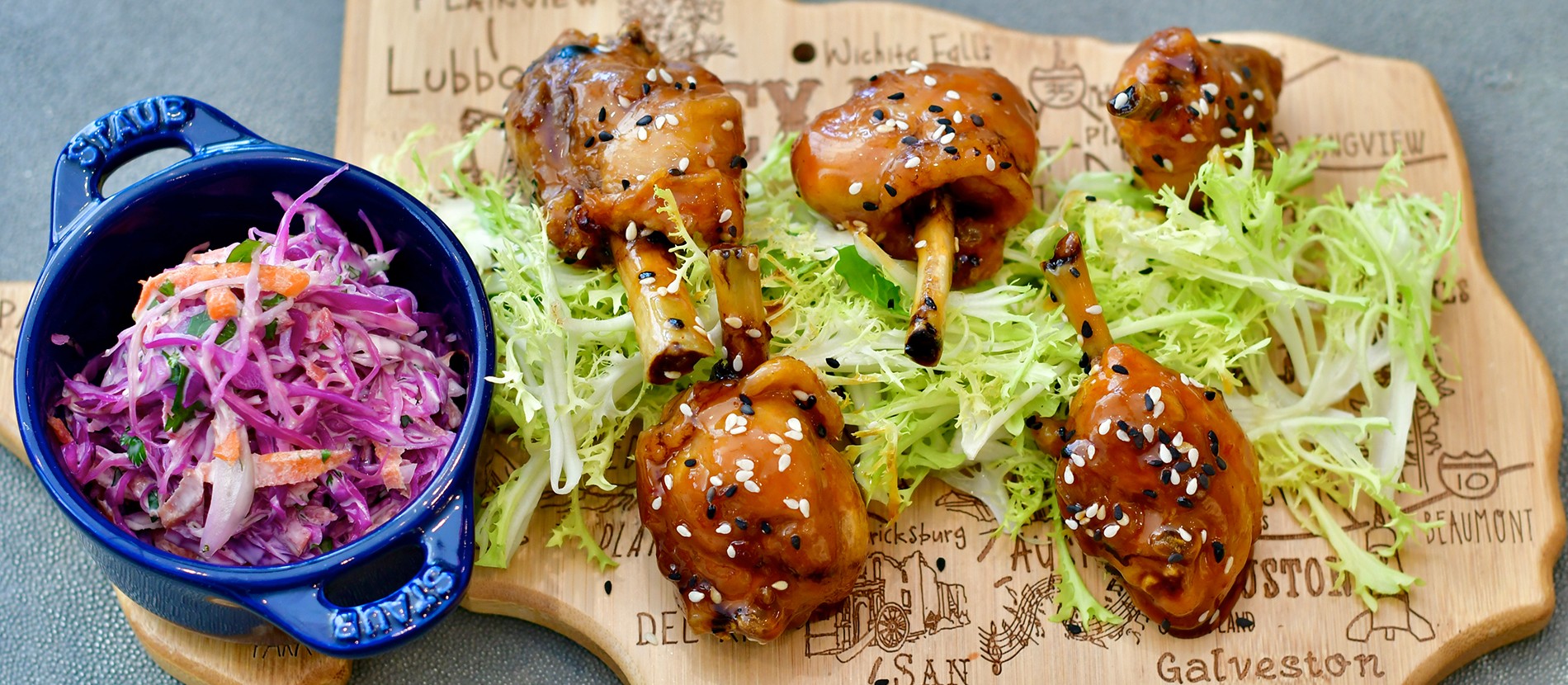 chicken lollipops on a bed of green lettuce and coleslaw side