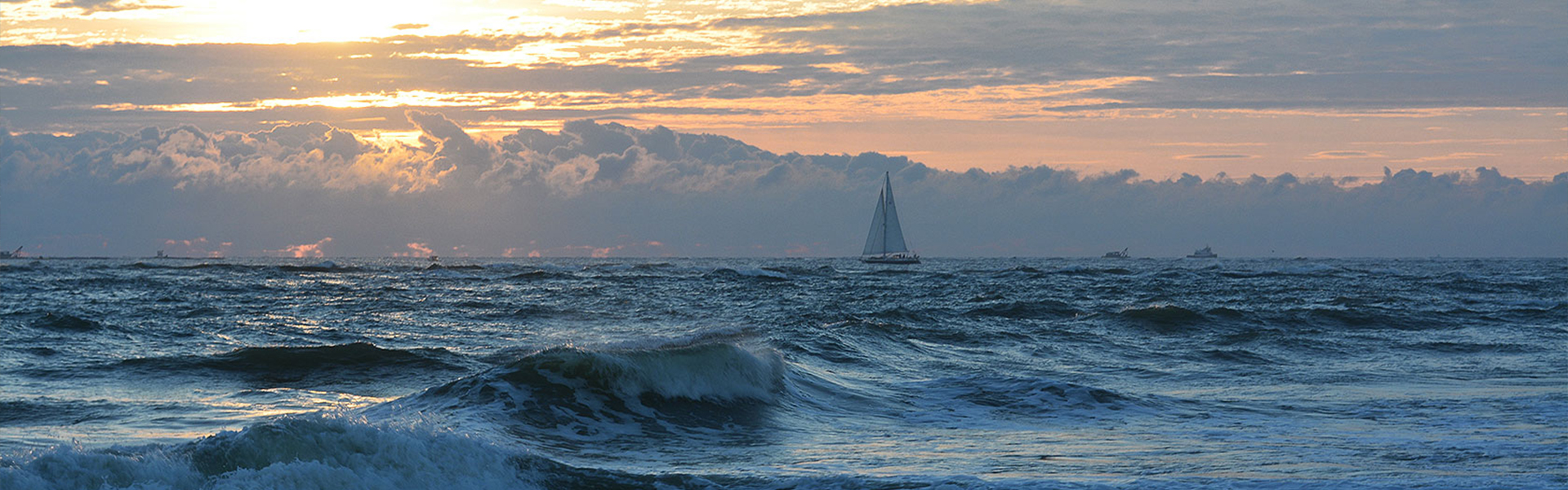 Vast ocean with sailboat in the distance