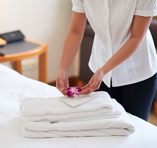 Hotel housekeeper placing a flower on a stack of towels