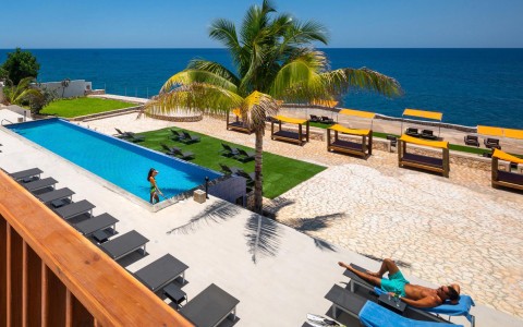 hotel pool and pool chairs with a beachfront view