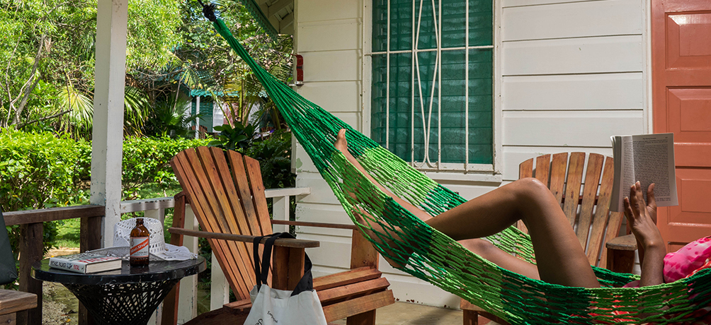 woman relaxing in hammock reading a book in front of bungalow