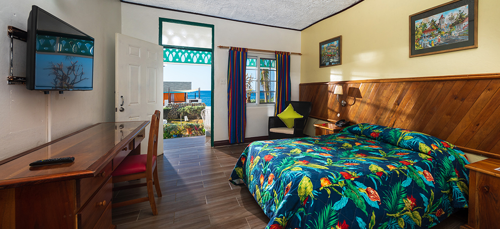 spacious view of guest room with tropical linens and wooden accent furniture