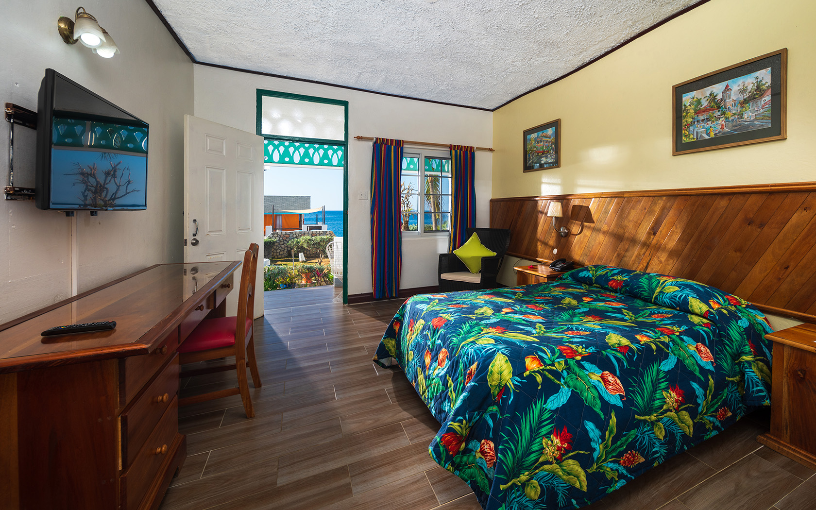 spacious guest room with tropical bedding linen and wooden furniture accents