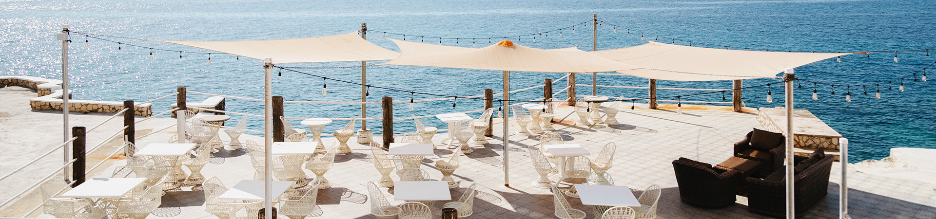 white umbrella covered ocean side seating area of restaurant