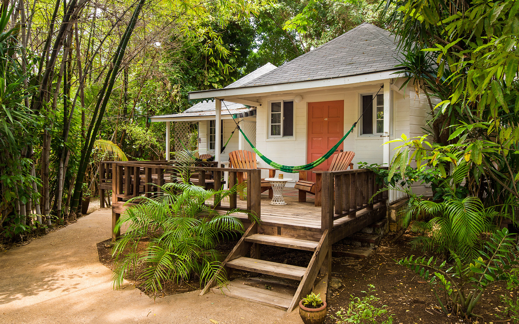 side angel of bungalow featuring a porch with hammock and seating area in tropical garden setting