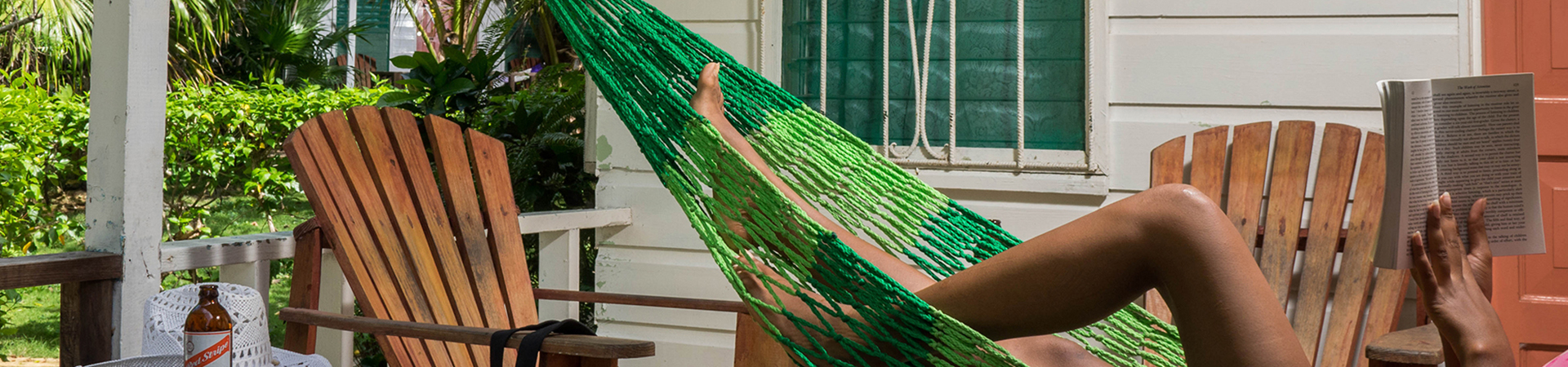 woman relaxing and reading book in green hammock on patio