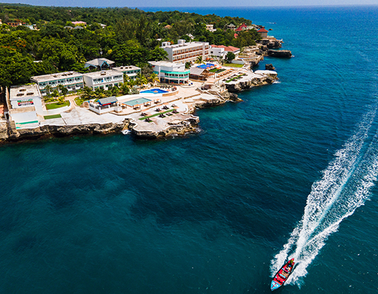 aerial view of resort property with view of speed boat cutting through ocean 