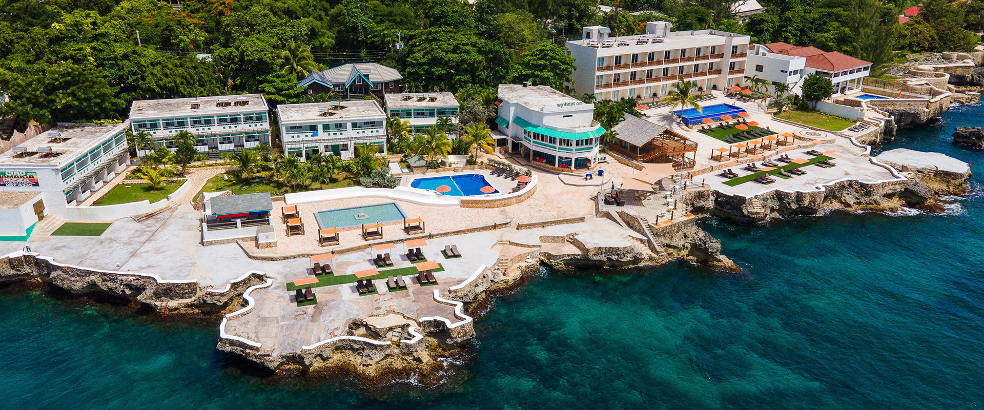 aerial view of resort property including guest lodging, pools, and lounge areas with ocean view