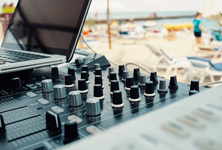 close up dj mixing board with background of beach and leisure area
