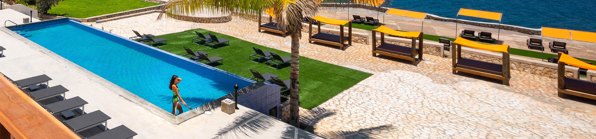 wide angel view of pool and seating area with cabanas in background