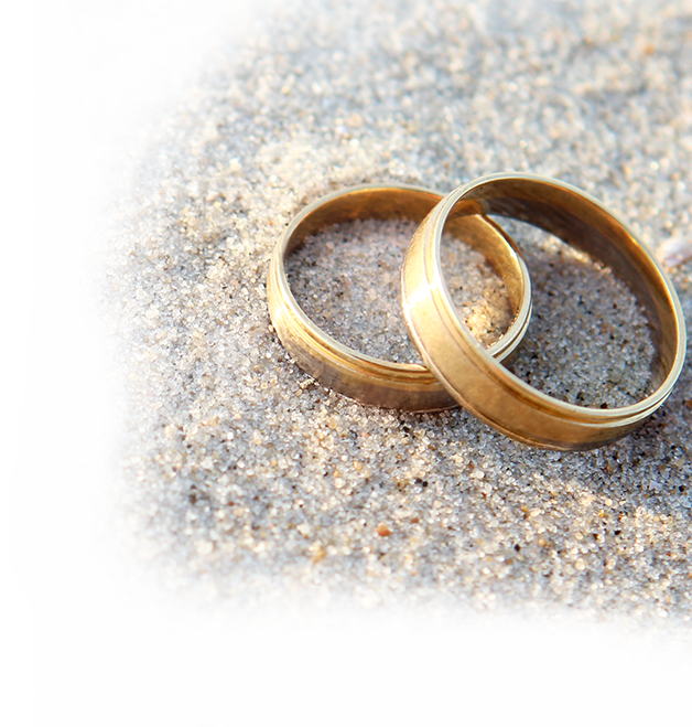 close up of wedding bands overlapped on one another set on sand
