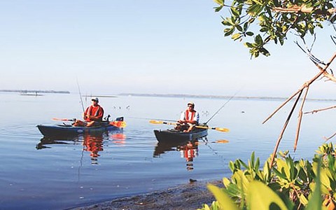 Two people fishing on kayaks on a lake 