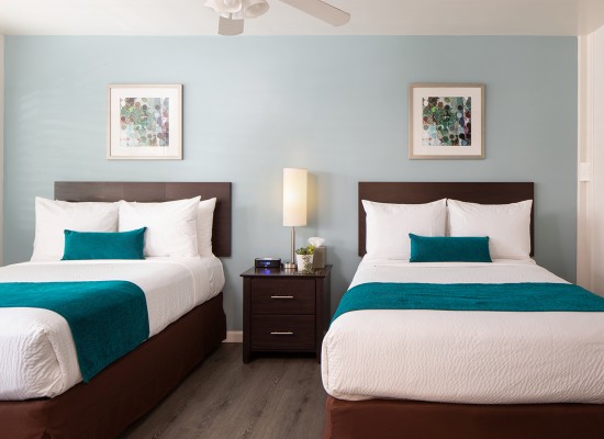 light blue room with two double beds with blue blankets