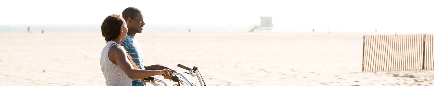 Man and woman riding bike on the beach