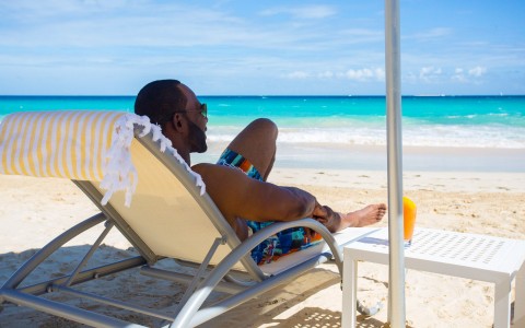 view of a guy wearing sun glasses enjoying the day in a beach chair at the beach 