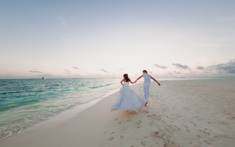 bride and groom running enjoying their marriage at the beach