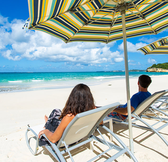 two guys enjoying the day at the beach sitting in two chairs