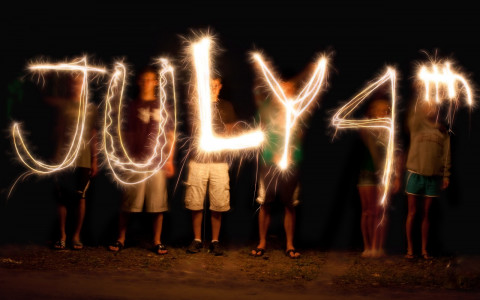 Children writing July 4th in the air with sparklers