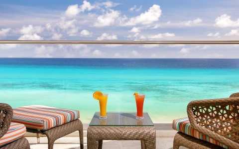 balcony overlooking the ocean with 2 drinks on the table