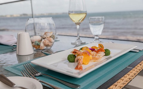shrimp and veggies on a plate next to a glass of wine