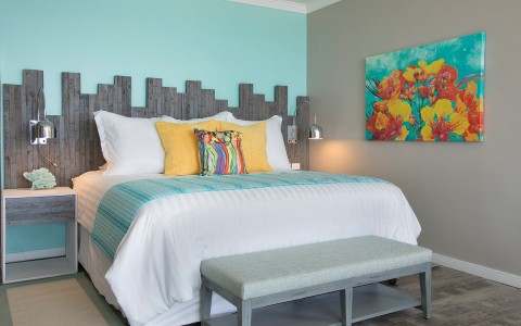 bed with blue striped bedrunner with flower painting on the wall